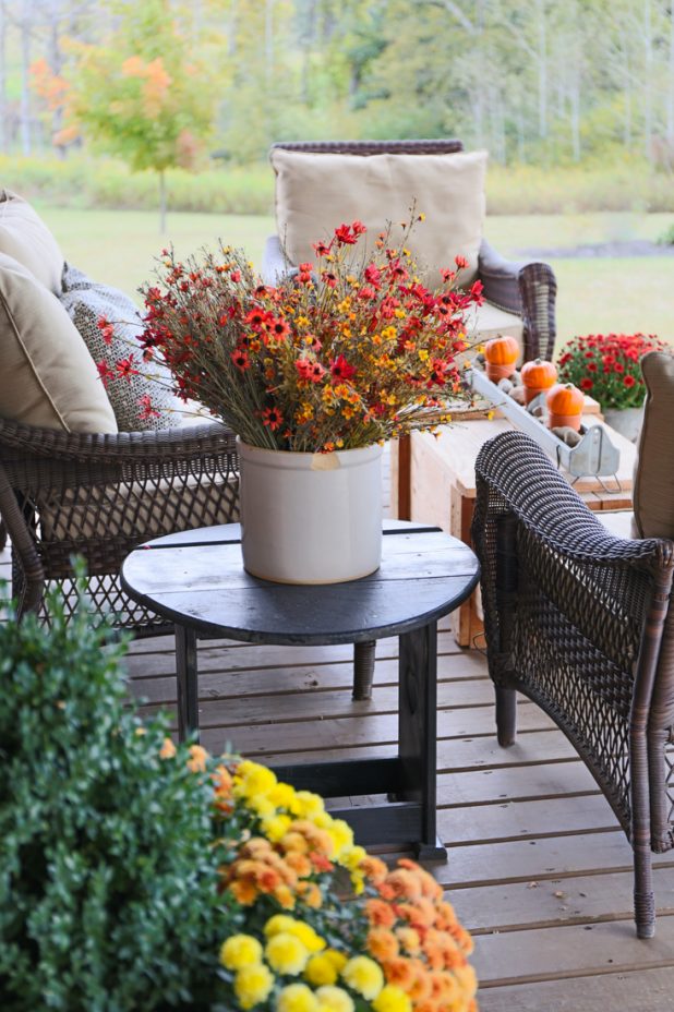 Rustic Fall Porch of a Log Home Decorated With Mums and Pumpkins