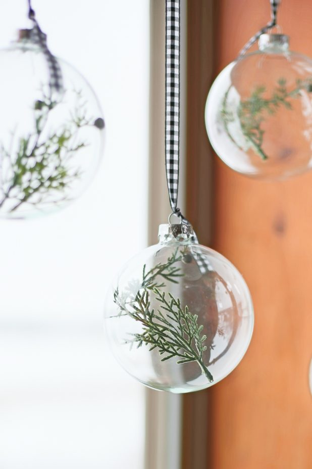 DIY Christmas Window Treatment Using Clear Glass Ornaments and Pine Clippings Hung From a Curtain Rod With Ribbon