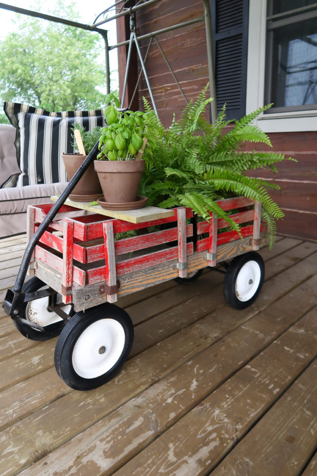 Vintage Red Wagon Used as a Coffee Table to Hold Herbs and Plants On The Covered Porch